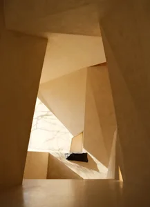 Modern, minimalist interior design featuring concrete walls and floors with geometric shapes and natural light.