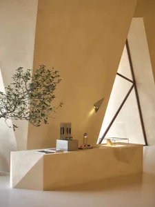 A modern office space with a concrete desk and plants, featuring geometric shapes and a triangular window.