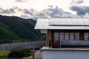 A modern residential exterior featuring a corrugated metal roof and a concrete foundation.