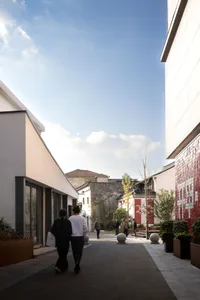 Street scene with concrete pavement, green plants, pedestrians, and buildings
