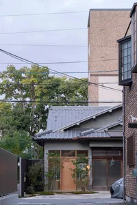 Street view featuring a tile-roof, concrete, and brick building with a car parked in front and power lines overhead.