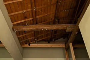 Editorial photograph of a wooden ceiling with exposed beams and wiring
