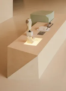 A minimalist product display featuring a sculpture, a cube, and various business cards on a light-colored, geometric platform