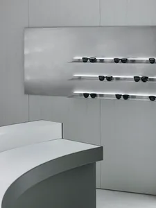 Minimalist glass counter with black metal shelves featuring black sunglasses in a retail storefront.