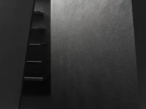 A minimalist staircase made of metal against a textured wall.