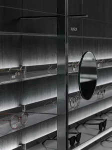 Modern minimalist optical shop showcasing black metal shelves displaying various eyeglasses.