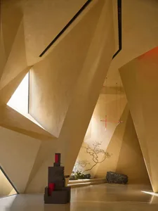 A modern interior space with concrete walls, a hanging light fixture, and geometric architectural features.