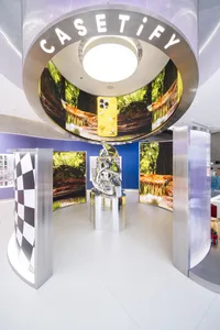 An immersive Casetify display featuring metallic sculptures and digital displays showcasing products and nature-inspired them