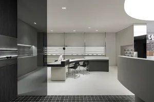 Modern retail eyewear store reception desk with minimalist design, featuring a white counter and black seating area.