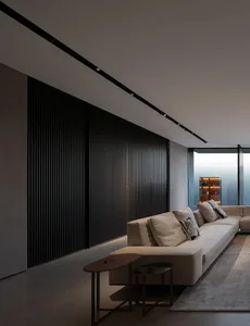 Modern living room featuring a beige sofa, concrete flooring, and large windows.