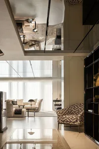 Modern living room featuring sleek, glass furniture with geometric patterns, large windows, and contemporary decor.