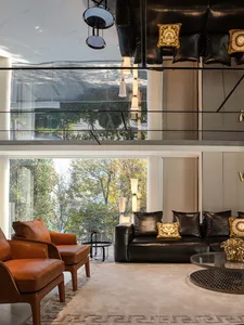 A modern living room with leather furniture, glass tables, marble accents, and wooden elements.
