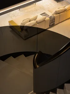 Modern lounge area with glass staircase and contemporary furniture.