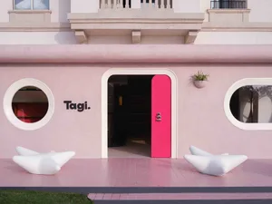 A minimalist storefront with a pink wall and a pink door.