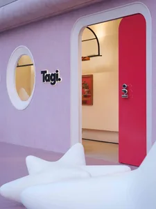 A minimalist storefront with a pink awning and white curved chairs.