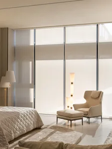A serene bedroom with a neutral color palette, featuring a bed, armchair, and floor lamp.