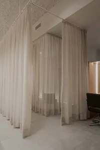 一間被白色紗簾圍繞的簡約醫療套房。