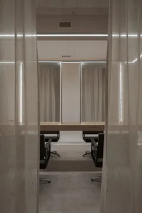 A minimalist office setting with a desk and chairs separated by curtains.