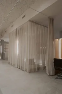 A minimalist office space featuring fabric curtains.