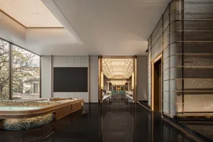 A sleek, modern hotel lobby featuring glass walls and a black marble floor.