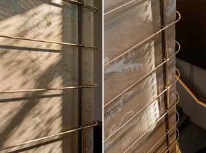 A modern interior with metallic textile blinds creating abstract patterns on the floor.