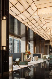 A modern lobby featuring marble flooring and walls with a warm, ambient lighting setup.