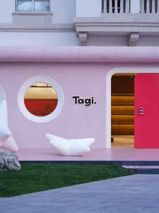 A modern storefront with a pink concrete facade and a circular window.