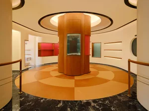 A modern retail shop interior with a central wooden pillar, glass display case, and black marble floor