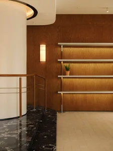 A modern retail shop with wooden walls featuring shelves and a staircase with a wooden rail.