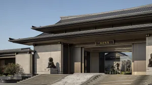 A stone exterior residential entryway with ornate steps and a traditional roof design.