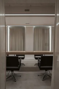 A modern hair salon station featuring a wooden countertop and glass panels.