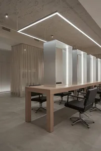 A modern salon interior with a wooden table and black chairs.