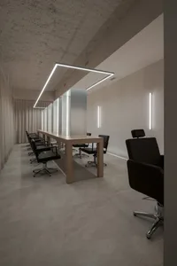 A minimalistic hair salon with concrete floors, glass partitions, and sleek chairs.