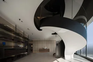 A modern lobby with glass spiral staircase, black and white color scheme, and minimalist design elements.