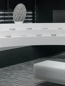 現代簡約的零售展示，採用金屬與壓克力鏡框陳列眼鏡，並搭配環境照明。