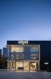 A modern Versace Home storefront illuminated at night with large glass windows displaying interior designs.