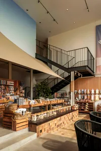 A spacious, industrial-style retail shop with a black metal staircase and a display case showcasing various goods.
