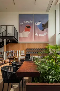 Modern coffee shop interior with wooden tables, metal chairs, and glass display cases.