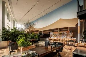 A modern coffee shop with brick walls, wooden tables, and metal shelving.
