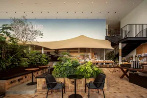 An industrial-style cafe interior with wooden tables, concrete walls, and metal accents.