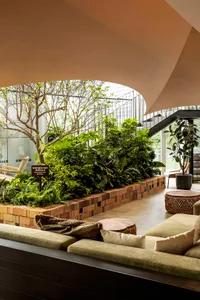 Industrial-style office space featuring exposed brick walls, concrete flooring, and lush greenery plantings in a contemporary