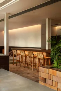 A modern bar with wooden stools and concrete walls.