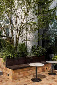 Outdoor seating area with brick walls, concrete floor, and green plants.