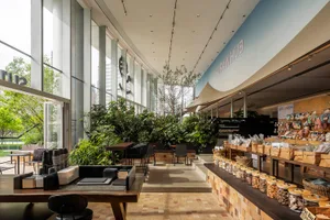A spacious pet shop interior with modern design, featuring large windows, wooden shelves, and a lush plant-filled interior sp