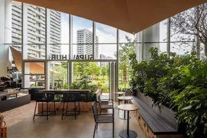 Modern restaurant cafe with green plants, large glass windows, and a concrete floor.