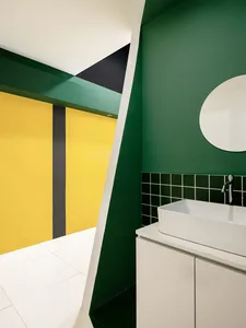 Modern bathroom with green painted walls, yellow accents, and green tiles