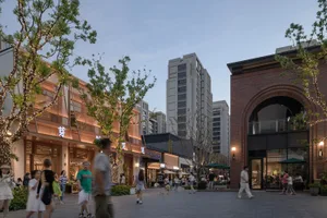 A bustling commercial mall with modern architecture featuring brick, concrete, glass, and lighting.