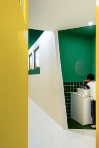 A modern public toilet interior with green and white colors, ceramic tiles, and a sink.