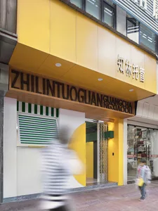 A vibrant street facade with a yellow metal frame and green and white striped door.