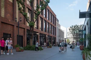 人們走在現代都市街景的磚鋪人行道上，兩旁是玻璃櫥窗店面。